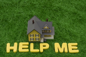 House with the words help me on grass. mortgage crisis